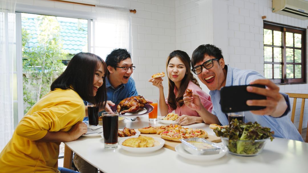 happy young group having lunch home asia family party eating pizza food making selfie with her friends birthday party dining table together house celebration holiday togetherness